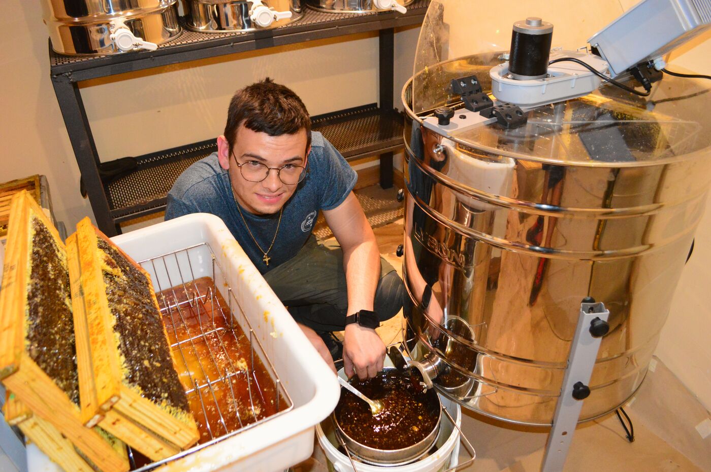 Pablo recogiendo la miel decantada del desoperculador, junto al extractor.